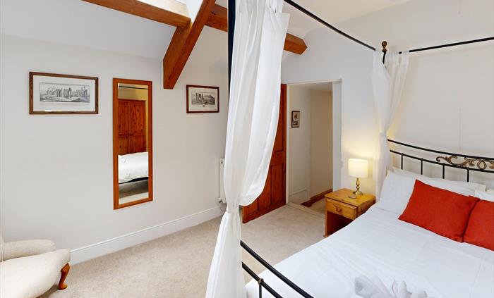 Bright master bedroom featuring a four-poster bed, skylight, and traditional furnishings.